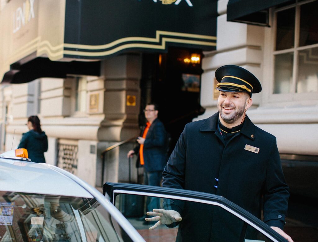A valet employee closing the door for a guest in front of the Lenox Hotel in Boston