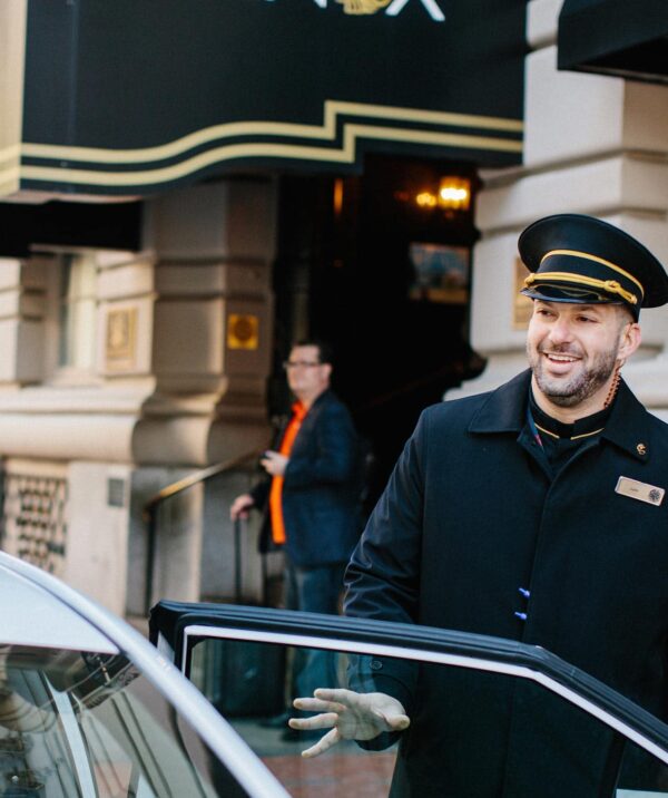 A valet employee closing the door for a guest in front of the Lenox Hotel in Boston